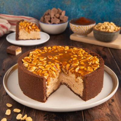Torta Snickers con crosta al cioccolato, cuore cremoso, arachidi e caramello colante in superficie