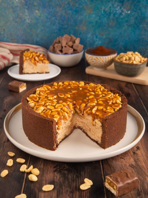 Torta Snickers con crosta al cioccolato, cuore cremoso, arachidi e caramello colante in superficie