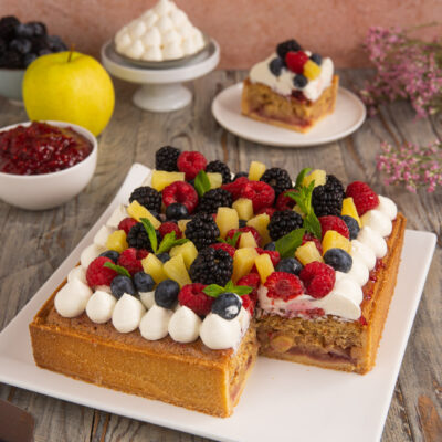 Torta Sonia farcita con mele e confettura, decorata con ciuffi di panna e frutti di bosco freschi