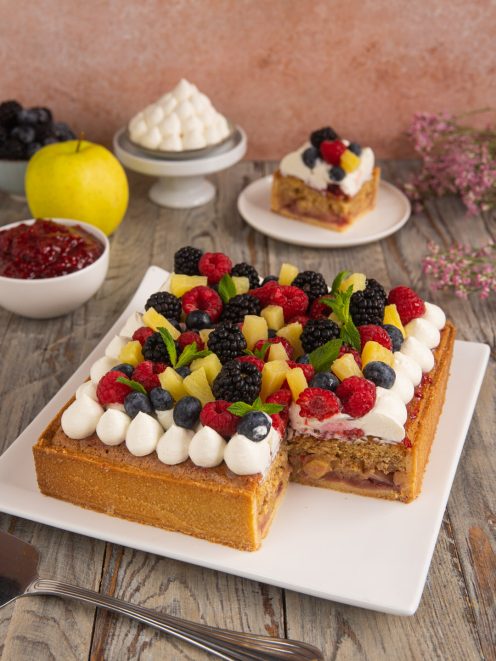 Torta Sonia farcita con mele e confettura, decorata con ciuffi di panna e frutti di bosco freschi