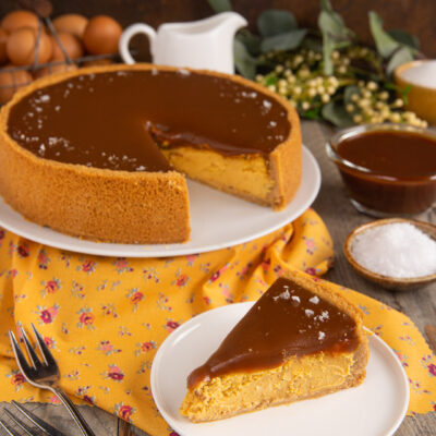 Cheesecake al caramello salato con glassa lucida e fiocchi di sale in superficie, fetta pronta da servire