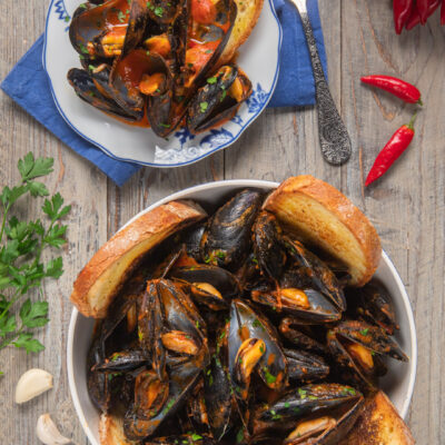 Cozze alla tarantina in salsa di pomodoro piccante con crostoni di pane e prezzemolo fresco