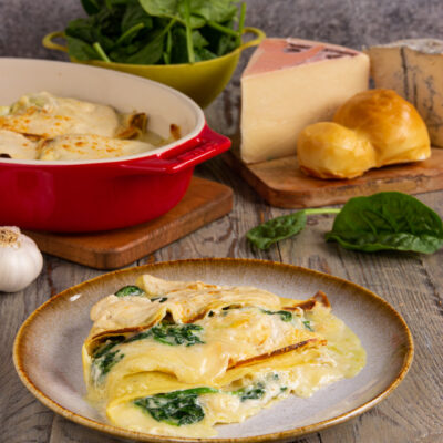 Crespelle ai 4 formaggi e spinaci gratinate servite su piatto con strati filanti in vista