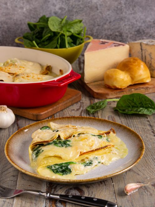 Crespelle ai 4 formaggi e spinaci gratinate servite su piatto con strati filanti in vista