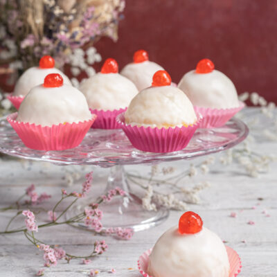 Dolci della sposa glassati di bianco con ciliegina candita sopra, serviti in pirottini rosa
