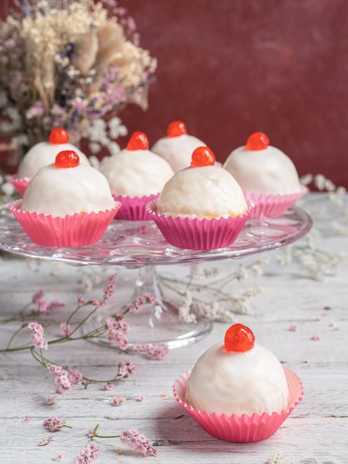 Dolci della sposa glassati di bianco con ciliegina candita sopra, serviti in pirottini rosa