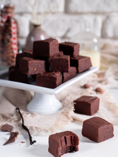 Fudge al cioccolato tagliato a cubotti impilati, con un pezzo morso in primo piano