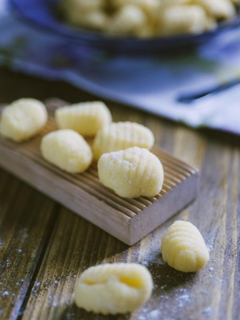 Gnocchi di semolino freschi rigati appoggiati su un rigagnocchi di legno infarinato