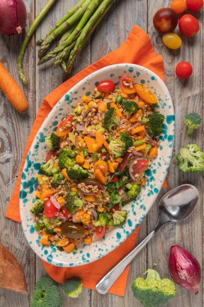 Insalata di farro con broccoli, pomodorini, carote e cipolla rossa servita su vassoio ovale