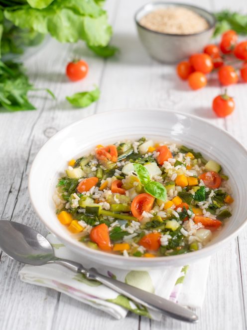 Minestrone di verdure con riso, pomodorini, zucchine e carote guarnito con basilico fresco