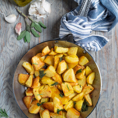 Patate in padella dorate con foglie di salvia e rosmarino
