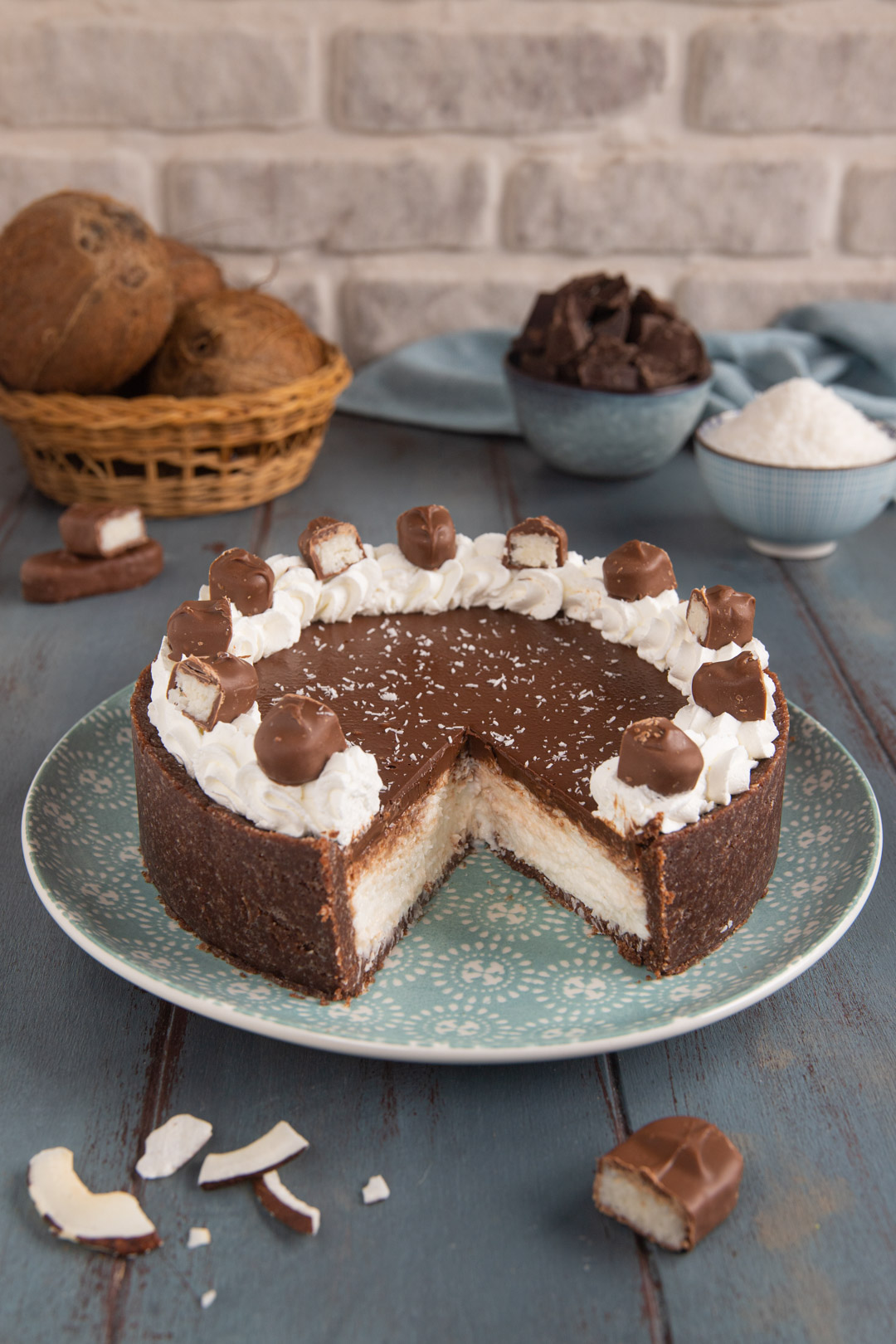 Torta Bounty tagliata con ciuffi di panna montata, cocco grattugiato e mezzi Bounty sopra