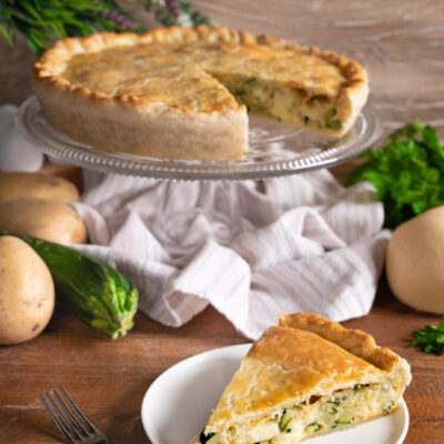 Torta salata con zucchine, patate e scamorza, tagliata a fette con crosta dorata