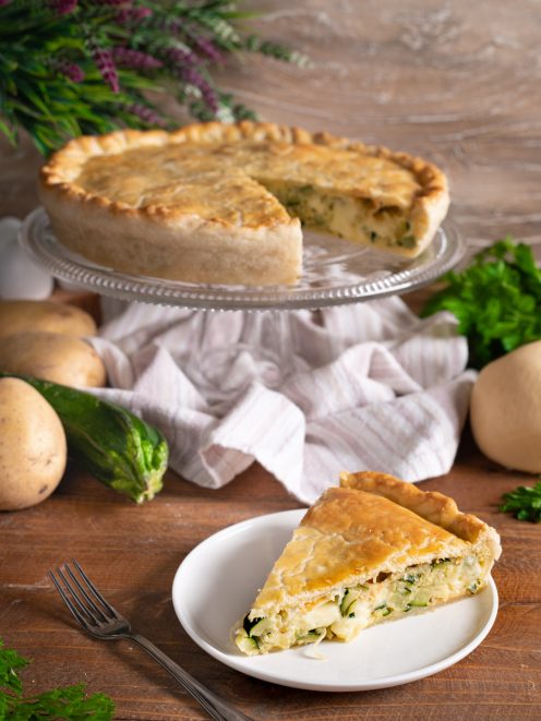Torta salata con zucchine, patate e scamorza, tagliata a fette con crosta dorata