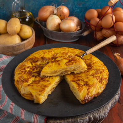 Tortilla de patatas dorata con patate a strati, affettata e servita intera