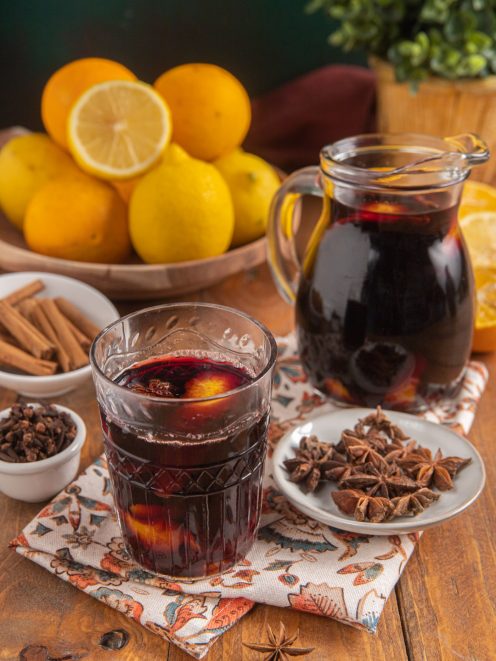 Vin brulé servito in un bicchiere con fette d'arancia, anice stellato e cannella