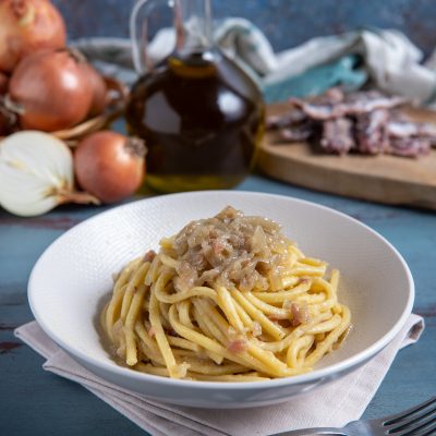 Bigoli in salsa con cipolla stufata e acciughe, avvolti in un sugo denso e saporito