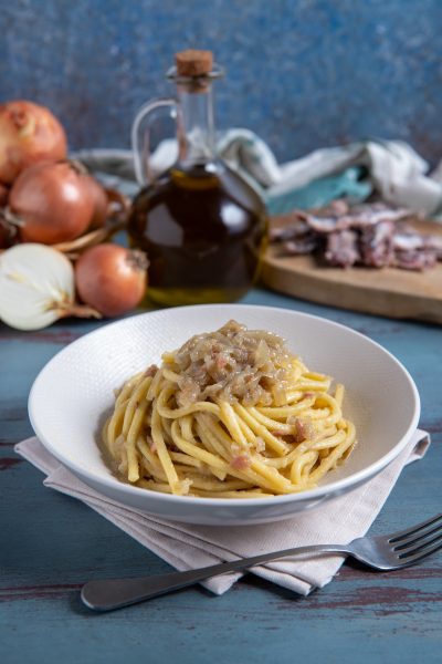 Bigoli in salsa con cipolla stufata e acciughe, avvolti in un sugo denso e saporito