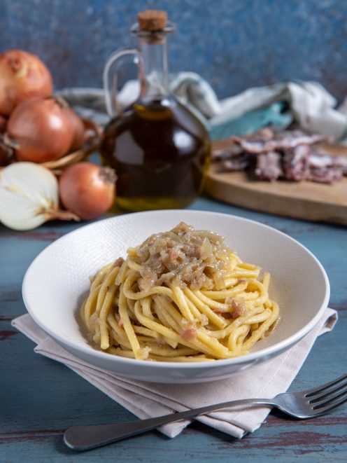 Bigoli in salsa con cipolla stufata e acciughe, avvolti in un sugo denso e saporito