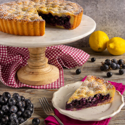 Crostata di uva fragola con una fetta servita al piatto, zucchero a velo in superficie