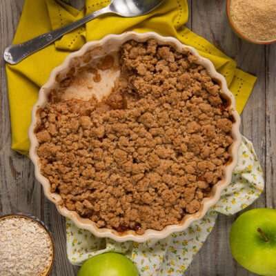 Crumble di mele appena sfornato con copertura croccante di frolla in una teglia rotonda