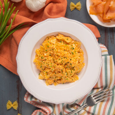 Farfalle al salmone con salsa cremosa arancione e erba cipollina tritata