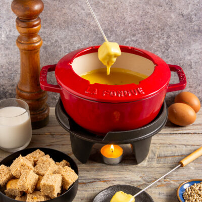 Fonduta alla valdostana con un cubetto di pane inzuppato nel formaggio fuso filante