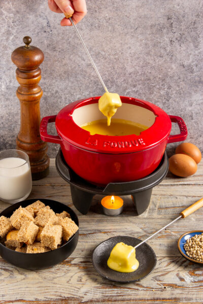 Fonduta alla valdostana con un cubetto di pane inzuppato nel formaggio fuso filante