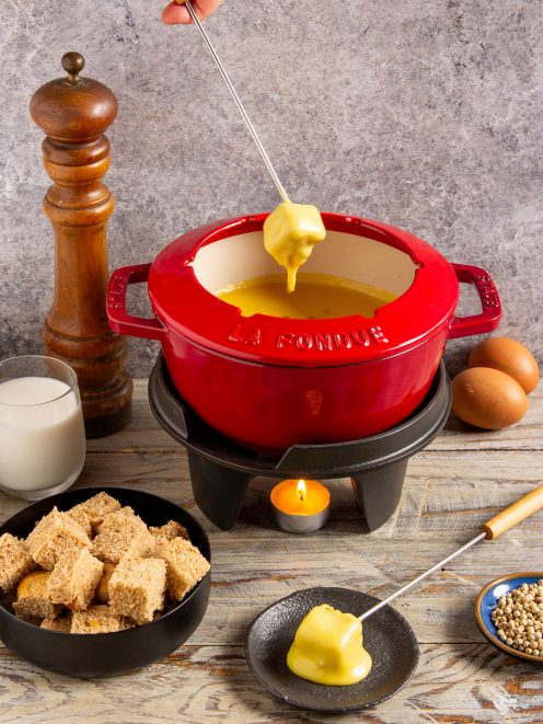 Fonduta alla valdostana con un cubetto di pane inzuppato nel formaggio fuso filante