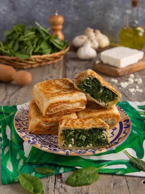 Gozleme con spinaci e feta tagliato a metà, con il ripieno verde ben visibile