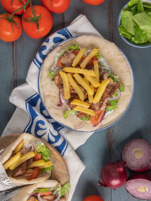 Pita gyros aperta con carne, patatine fritte, pomodoro, cipolla rossa e salsa tzatziki