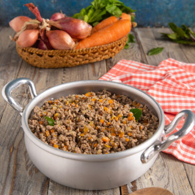 Ragù bianco con carne macinata, carote e cipolla tritata, guarnito con foglie di basilico