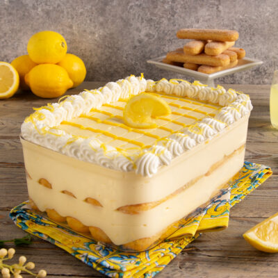 Tiramisù al limoncello con strati di savoiardi, crema al limone, ciuffi di panna e scorza grattugiata
