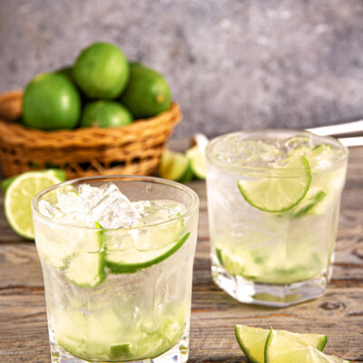 Caipirinha con ghiaccio tritato e fette di lime in due bicchieri