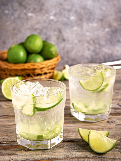 Caipirinha con ghiaccio tritato e fette di lime in due bicchieri