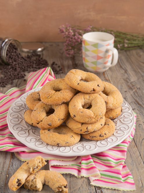 Ciambelline da inzuppo con gocce di cioccolato impilate su un piatto e spezzate a metà
