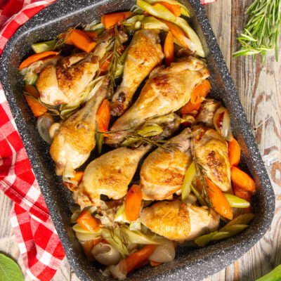 Cosce di pollo al forno dorate con carote, porri e rametti di rosmarino