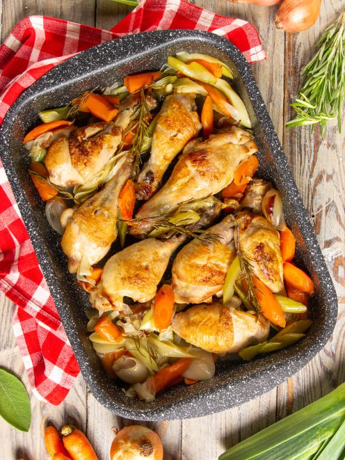 Cosce di pollo al forno dorate con carote, porri e rametti di rosmarino