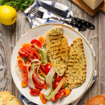 Cotoletta palermitana alla griglia con panatura alle erbe, servita con insalata di pomodori e verdure a julienne