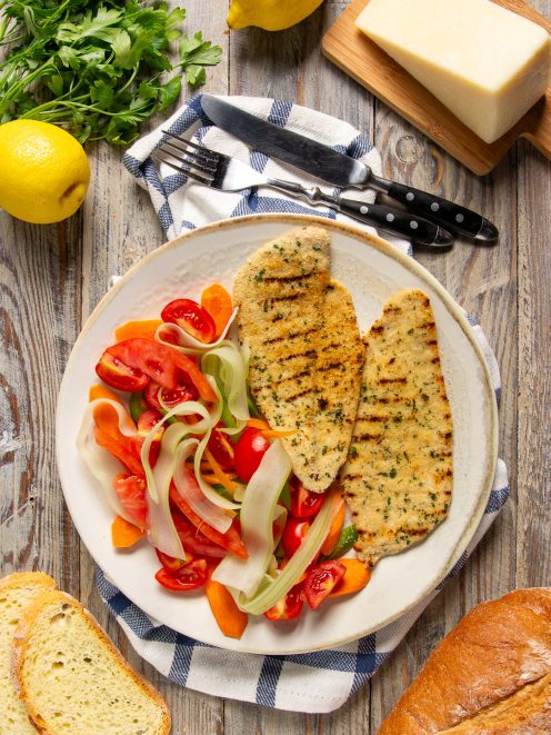 Cotoletta palermitana alla griglia con panatura alle erbe, servita con insalata di pomodori e verdure a julienne