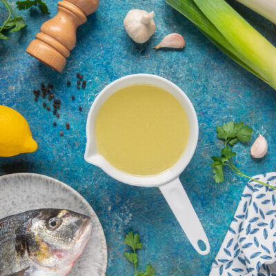 Fumetto di pesce in una salsiera con branzino fresco, porro, aglio, limone e prezzemolo