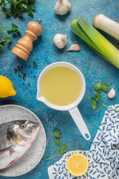Fumetto di pesce in una salsiera con branzino fresco, porro, aglio, limone e prezzemolo