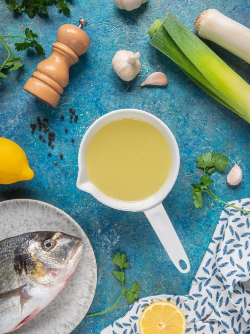 Fumetto di pesce in una salsiera con branzino fresco, porro, aglio, limone e prezzemolo