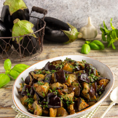 Melanzane in padella a cubetti, saltate e condite con erbe aromatiche tritate