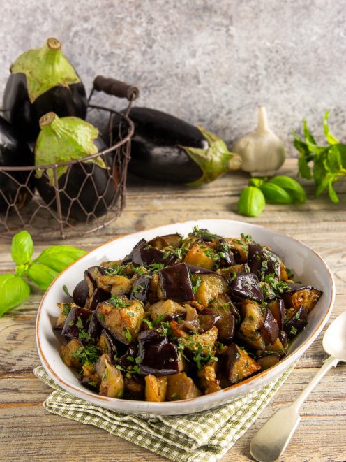 Melanzane in padella a cubetti, saltate e condite con erbe aromatiche tritate
