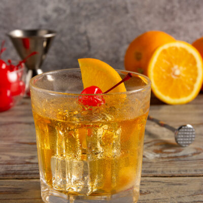 Old Fashioned con ghiaccio, guarnito da una fetta d'arancia e una ciliegia al maraschino