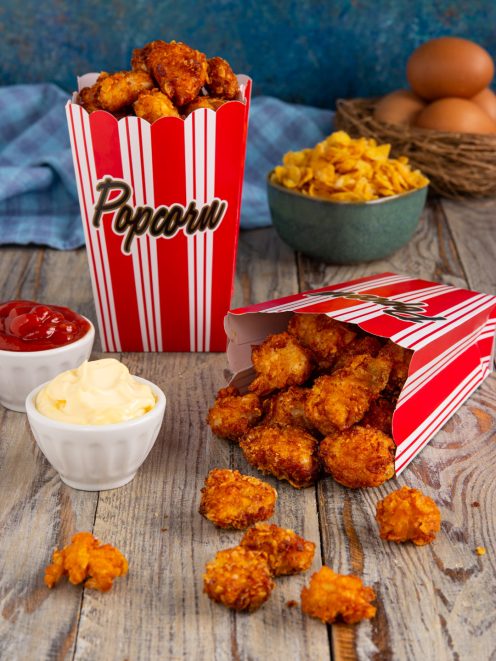 Popcorn di pollo croccanti in coppette da popcorn con ketchup e maionese per accompagnare