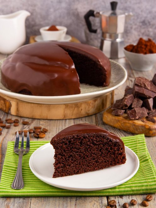 Torta brasiliana ricoperta di glassa al cioccolato lucida con una fetta tagliata a mostrare l'interno soffice