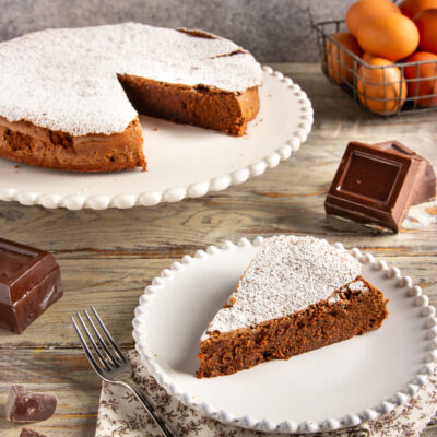 Torta cioccolatino con una fetta servita, spolverata di zucchero a velo