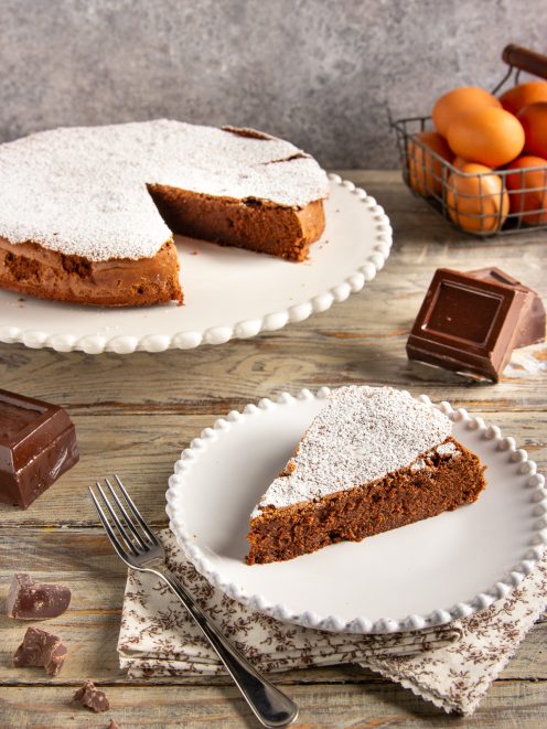 Torta cioccolatino con una fetta servita, spolverata di zucchero a velo